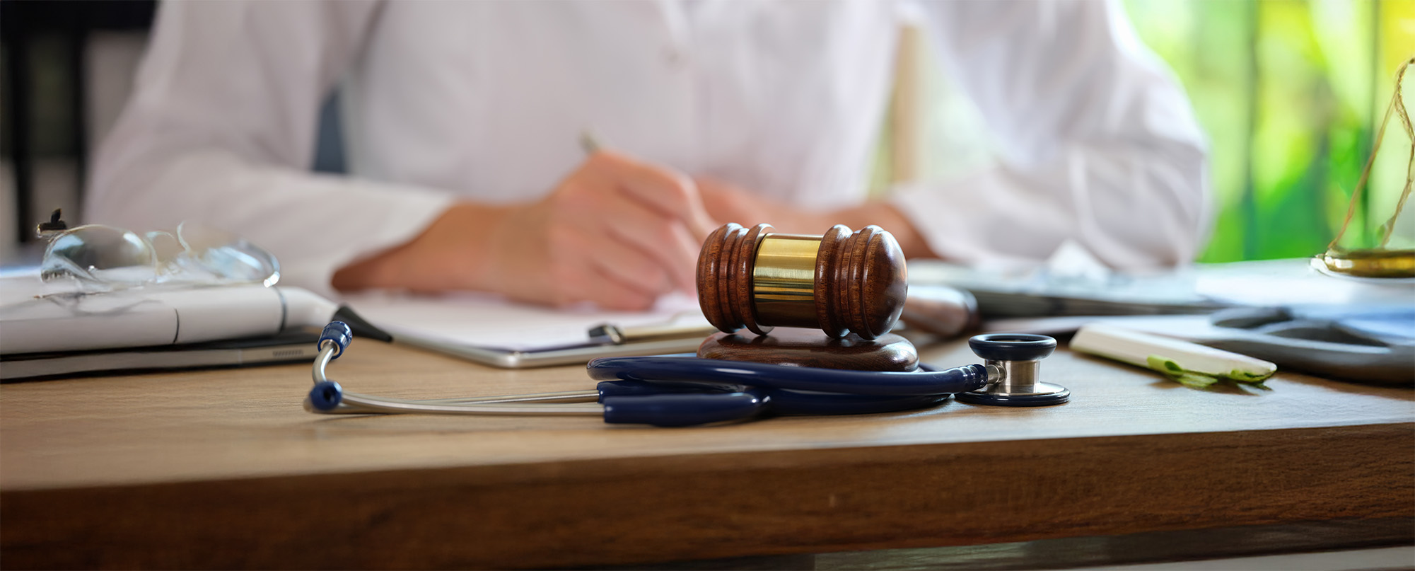 Court gavel with stethoscope on a table in background doctor writes notes