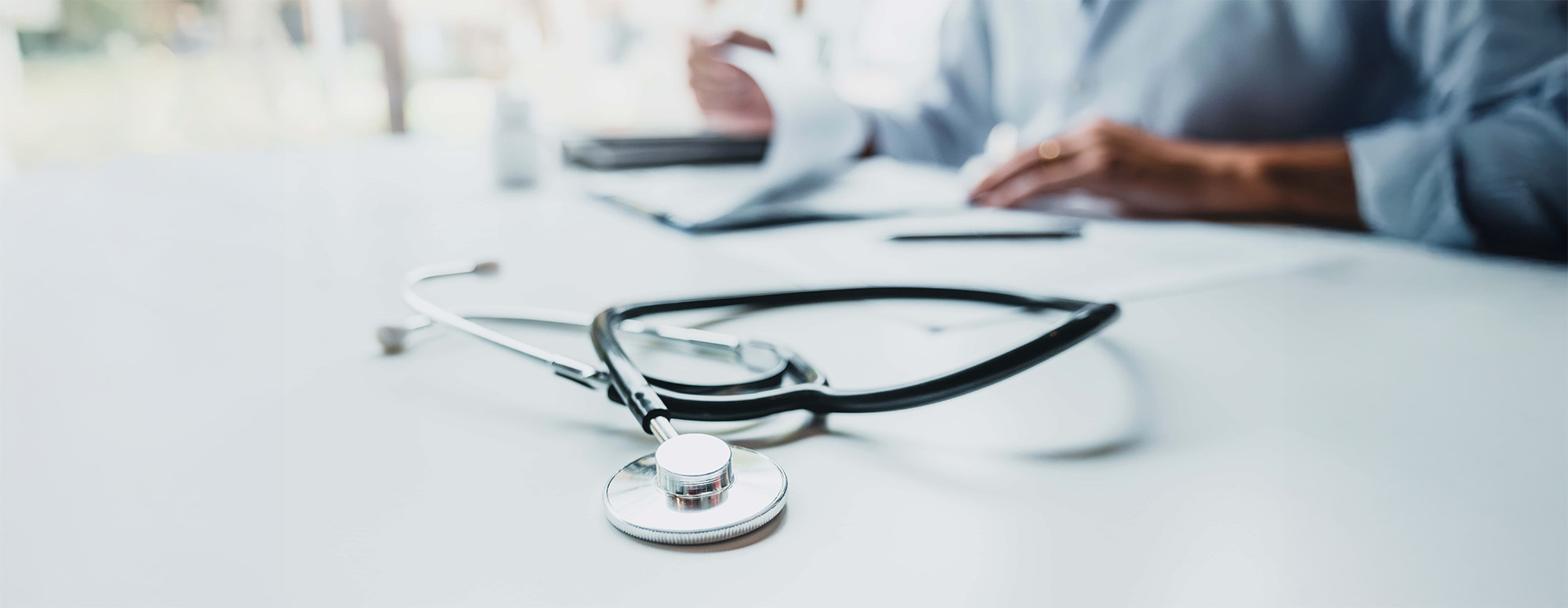 Doctor typing information on Laptop in Hospital office focus on Stethoscope