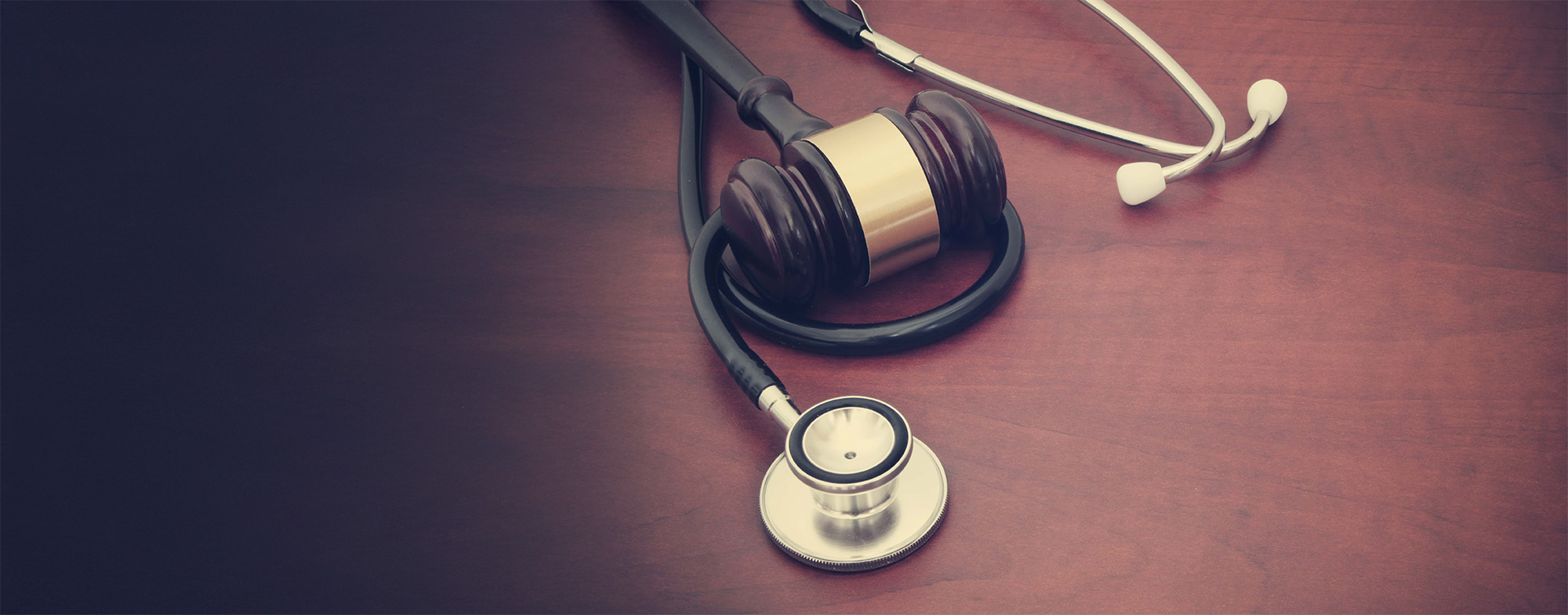 Wooden gavel and stethoscope on wooden background with copyspace